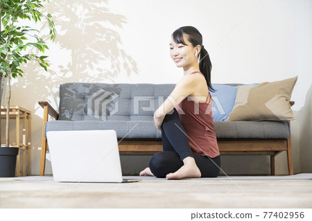 A woman doing yoga while looking at the computer screen A woman doing yoga while looking at the computer screen 77402956