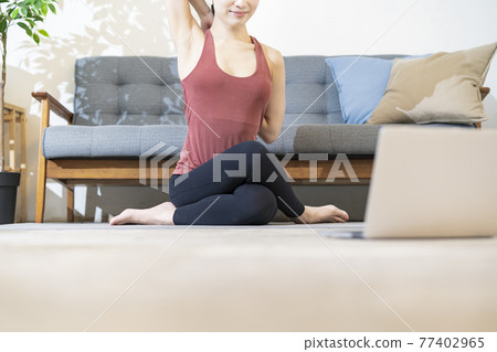 A woman doing yoga while looking at the computer screen A woman doing yoga while looking at the computer screen 77402965
