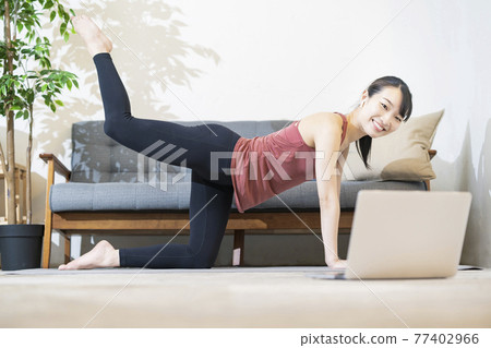 A woman doing yoga while looking at the computer screen 77402966
