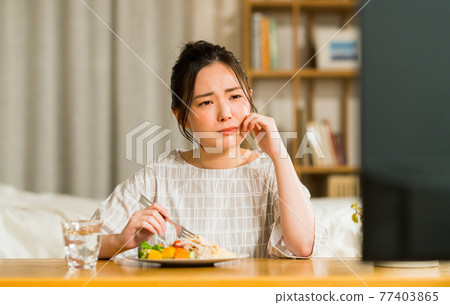 晚上看電視時吃東西的年輕女人 77403865