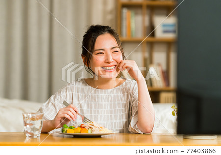 晚上看電視時吃東西的年輕女人 77403866