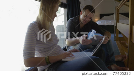 Man and woman talking while using pad and laptop 77405223