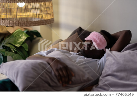 Handsome ethnic black african man resting in bed sleeping or napping. 77406149