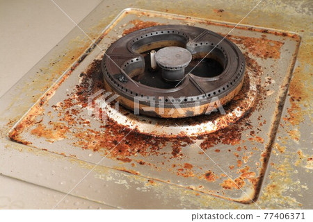 Dirty modern gas stove with cooking oil stains and burned food remnants on surface  77406371