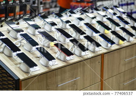 Smartphones store. Showcase with selling various new smartphones in electronics store during a sale. Mobile phone market concept Smartphones store. Showcase with selling various new smartphones in electronics store during a sale. Mobile phone market concept 77406537