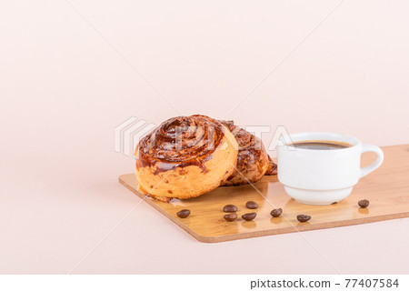 Two sweet cinnamon rolls and a cup of coffee. Two sweet cinnamon rolls and a cup of coffee. 77407584