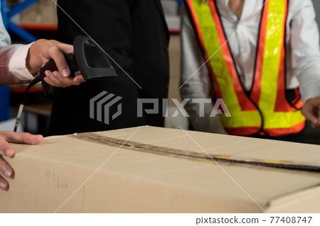 Warehouse worker using barcode scanner in storehouse 77408747