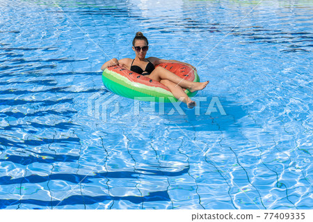 Summer fun. Happy young sexy girl in bikini swimsuit, sunglasses with inflatable rubber ring floating in blue pool water. Having fun and enjoying travel vacation. Swimming pool water. Summer fun. Happy young sexy girl in bikini swimsuit, sunglasses with inflatable rubber ring floating in blue pool water. Having fun and enjoying travel vacation. Swimming pool water. 77409335