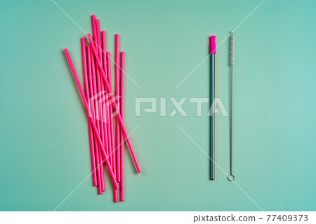The modern trend towards caring for the environment. A pack of pink plastic beverage straws versus one reusable beverage straw with cleaning brushes 77409373