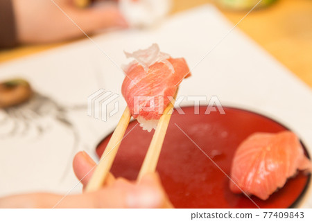 Hands of a man eating a fatty tuna Hands of a man eating a fatty tuna 77409843