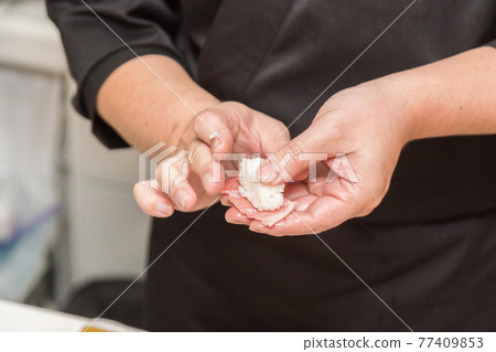 Hands of a sushi chef who holds sushi 77409853
