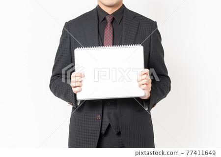 Male businessman with small sketchbook standing in front of white background 77411649