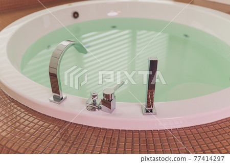 jacuzzi bath tub on marble floor with water. jacuzzi bath tub on marble floor with water. 77414297