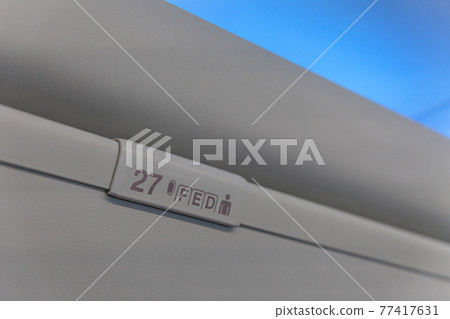Sign of seat number with number and letter on luggage shell inside passenger airplane Sign of seat number with number and letter on luggage shell inside passenger airplane 77417631