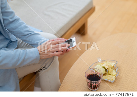 在自我克制的生活中在家使用智能手機的老年女性 在自我克制的生活中在家使用智能手機的老年女性 77417671