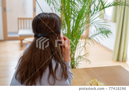 A middle-aged woman talking on her smartphone during her self-restraint 77418298