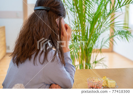 A middle-aged woman talking on her smartphone during her self-restraint 77418300