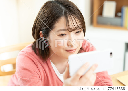 A young woman watching a smartphone A young woman watching a smartphone 77418888