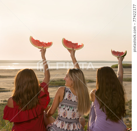 three girlfriends on a picnic, sitting turned away, holding watermelon slices, emotions and gestures three girlfriends on a picnic, sitting turned away, holding watermelon slices, emotions and gestures 77422177