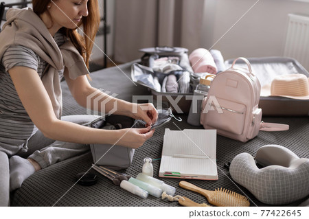 Smiling woman writing list of necessary cosmetics getting ready trip vacation storage organization 77422645