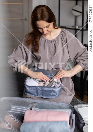 Unidentified woman puts lingerie in trip storage container use konmari method packing suitcase Unidentified woman puts lingerie in trip storage container use konmari method packing suitcase 77422654