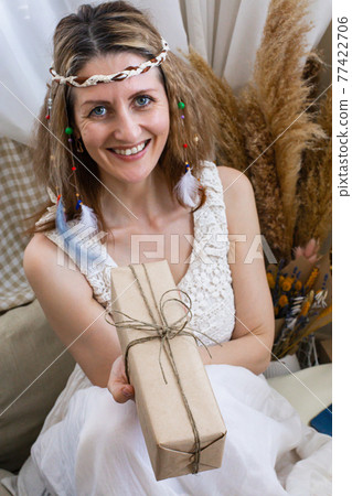 Portrait happy modern hippie female posing with craft wrapped gift box celebrating holiday Portrait happy modern hippie female posing with craft wrapped gift box celebrating holiday 77422706
