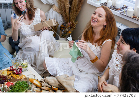 Happy redhead woman open gift box with bow enjoying celebrating holiday in boho scandi style Happy redhead woman open gift box with bow enjoying celebrating holiday in boho scandi style 77422708
