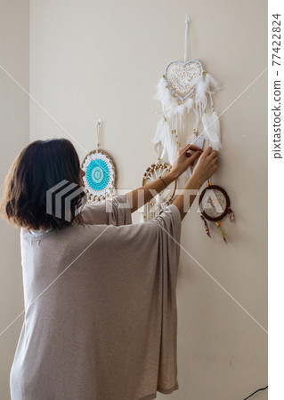 Elegant woman decorated beige home wall with boho scandi decor ethnic amulet dreamcatcher 77422824
