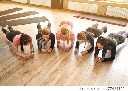 Group of young women doing plank together in gym Group of young women doing plank together in gym 77423131
