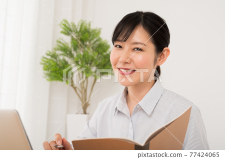 在電腦前拿著筆和筆記本工作的女人 77424065