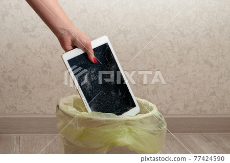 Woman throws it in the litter bin modern tablet with highly broken screen. 77424590