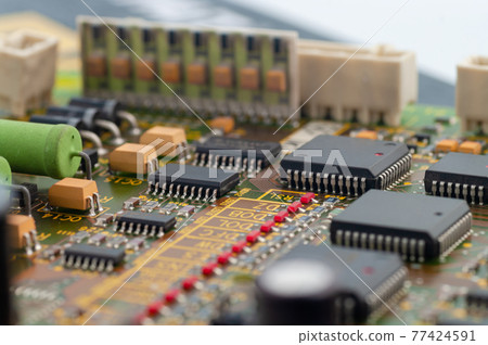 Close-up of electronic circuit board PCB with microchip, integrated circuits, resistances and electronic connections. 77424591