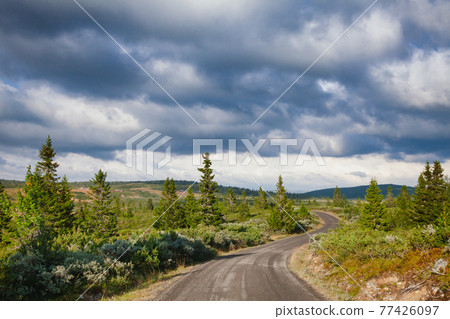 Rain clouds gloomy sky over winding scenic country road in Oppland Norway Scandinavia Rain clouds gloomy sky over winding scenic country road in Oppland Norway Scandinavia 77426097