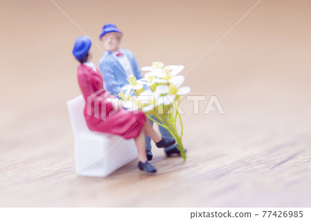 Couple sitting on a bench with a white bouquet 77426985
