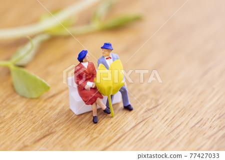 Rape blossoms and a couple sitting on a bench 77427033