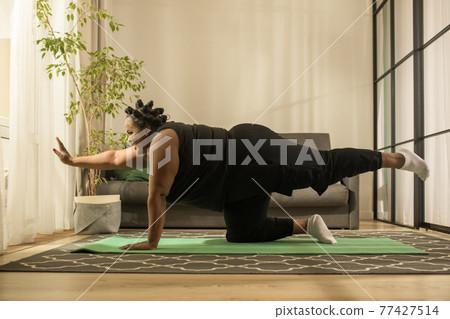 Blogger working on flexibility while filming blog about yoga at her apartments Blogger working on flexibility while filming blog about yoga at her apartments 77427514