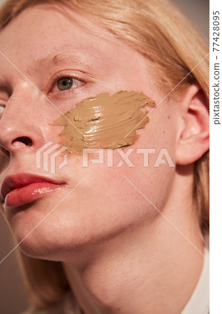 Feminine man looking away while posing with concealer at his chick 77428095