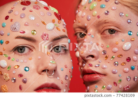 Albino boy with decor at his face looking at the camera while bonding to the mannish bald female Albino boy with decor at his face looking at the camera while bonding to the mannish bald female 77428109
