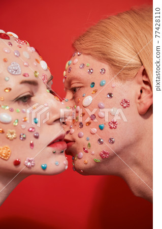 Mannish bald woman posing with albino feminine man over the red background Mannish bald woman posing with albino feminine man over the red background 77428110