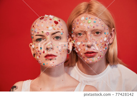 Albino feminine man and bald masculine woman with decor at their faces looking at the camera Albino feminine man and bald masculine woman with decor at their faces looking at the camera 77428142