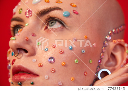 Woman with naked shoulders and decor at her face posing and looking away Woman with naked shoulders and decor at her face posing and looking away 77428145