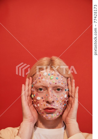 Albino man with decor at his face frames his head with his hands Albino man with decor at his face frames his head with his hands 77428173