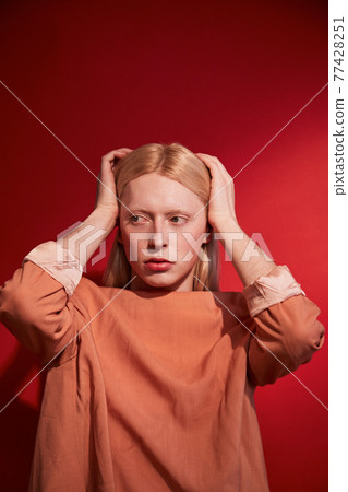 Albino feminine man straightens his hair and looking away 77428251