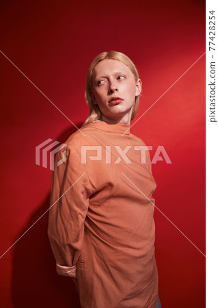 Man with womanly appearance standing at the studio and posing to the camera Man with womanly appearance standing at the studio and posing to the camera 77428254