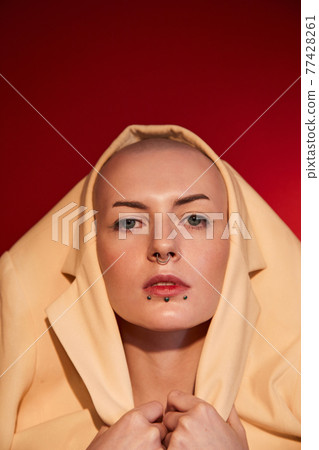 Female with masculine appearance wearing stylish jacket at her head posing at the studio Female with masculine appearance wearing stylish jacket at her head posing at the studio 77428261