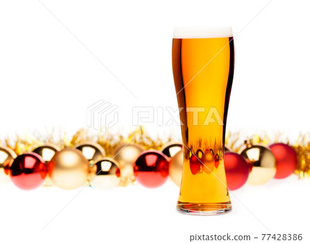 Tall glass of ale or beer with christmas baubles in background on white Tall glass of ale or beer with christmas baubles in background on white 77428386