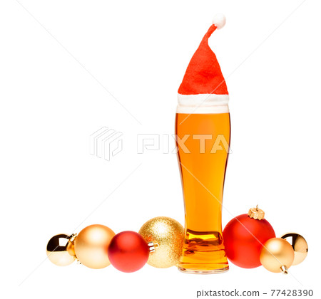Tall glass of ale or beer with with christmas red hat and baubles on white background Tall glass of ale or beer with with christmas red hat and baubles on white background 77428390