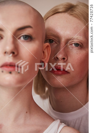 Womanly male with feminine features and masculine female with bald head and piercing at her face Womanly male with feminine features and masculine female with bald head and piercing at her face 77428716