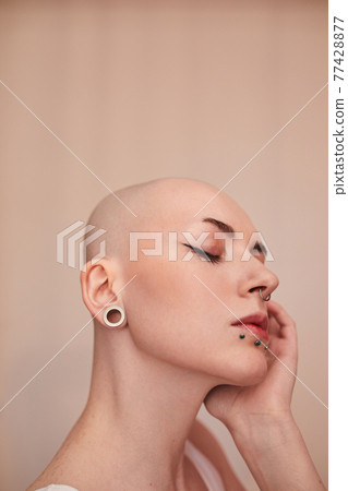 Serious female with blonde short hair and nude makeup looking away Serious female with blonde short hair and nude makeup looking away 77428877