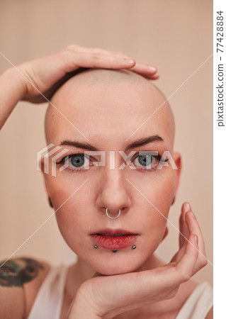 Masculine woman posing with hands at her head and looking at the camera Masculine woman posing with hands at her head and looking at the camera 77428884